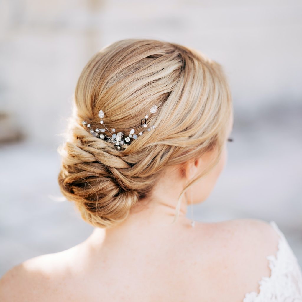 Blonde bride with a beautiful hairstyle and in a dress with bare shoulders, back view