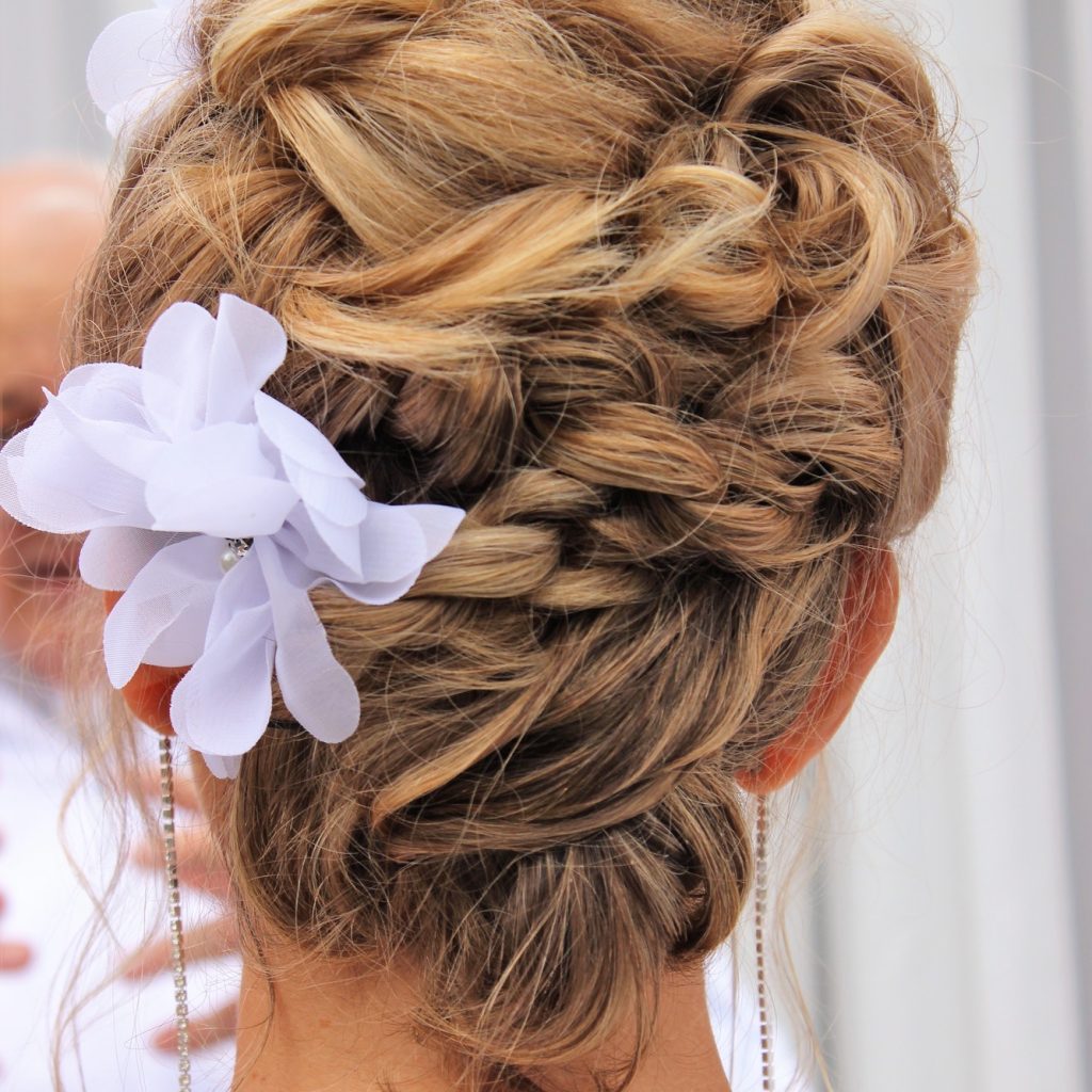 Blonde hair in a twisted up so with white flowers in some locks.