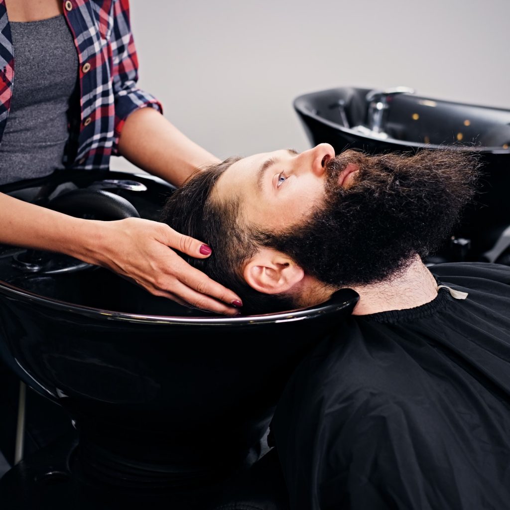 Hairdresser washing the hair of the bearded men.